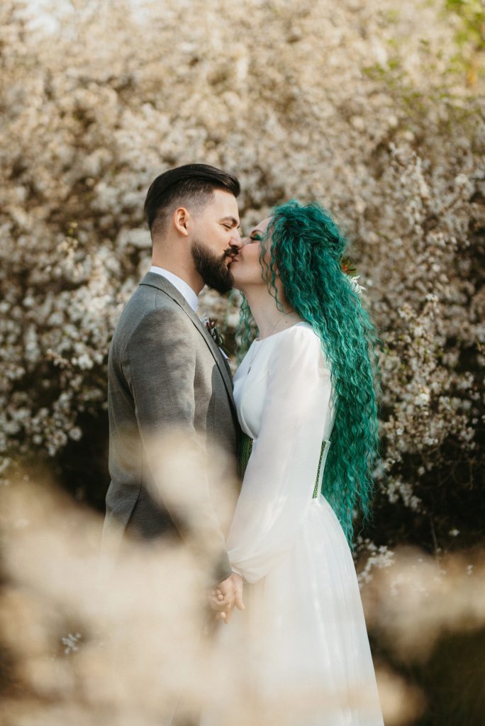 a bearded groom plays and a girl with green hair against the bac